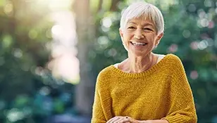 happy senior woman sitting at a table-308x175